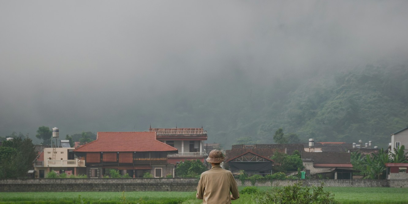 Man riding a bicycle on a path with rice fields either side in the Bac Son Valley, northern Vietnam